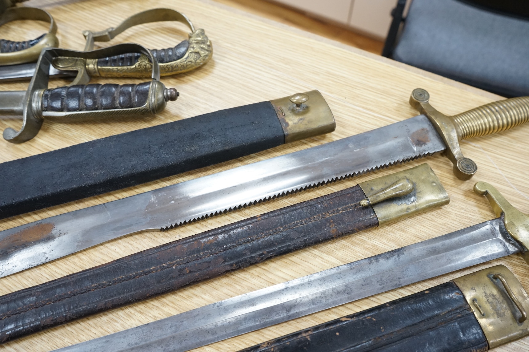 Three Continental infantry officer’s sidearms briquette, the first stamped Paris, in its brass mounted leather scabbard, another similar with sawback blade (illegible stamp), and another similar with thin blade, stamped